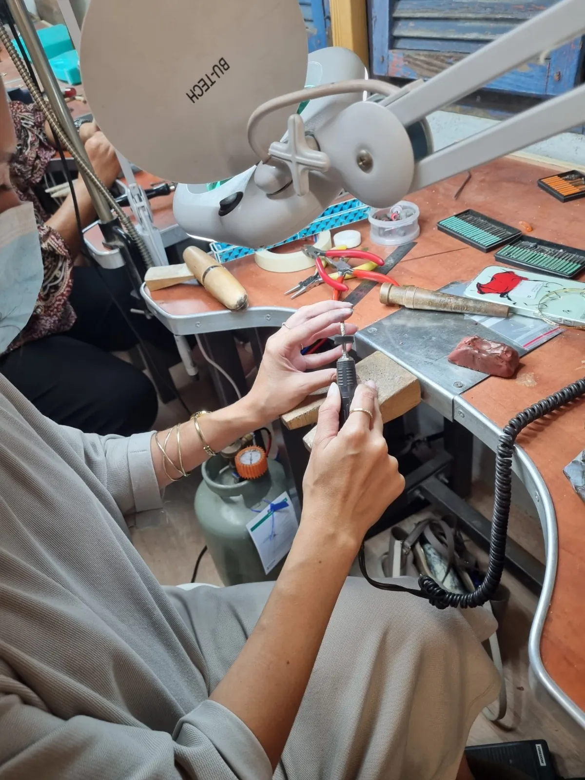 עבודת דיוק בעמדת הצורפות תחת מנורת זכוכית מגדלת עם מקדחה גמישה
